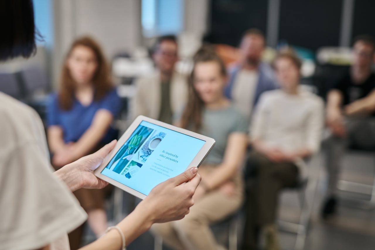 services-bg Business seminar with participants focused on a tablet presentation in an office setting.
